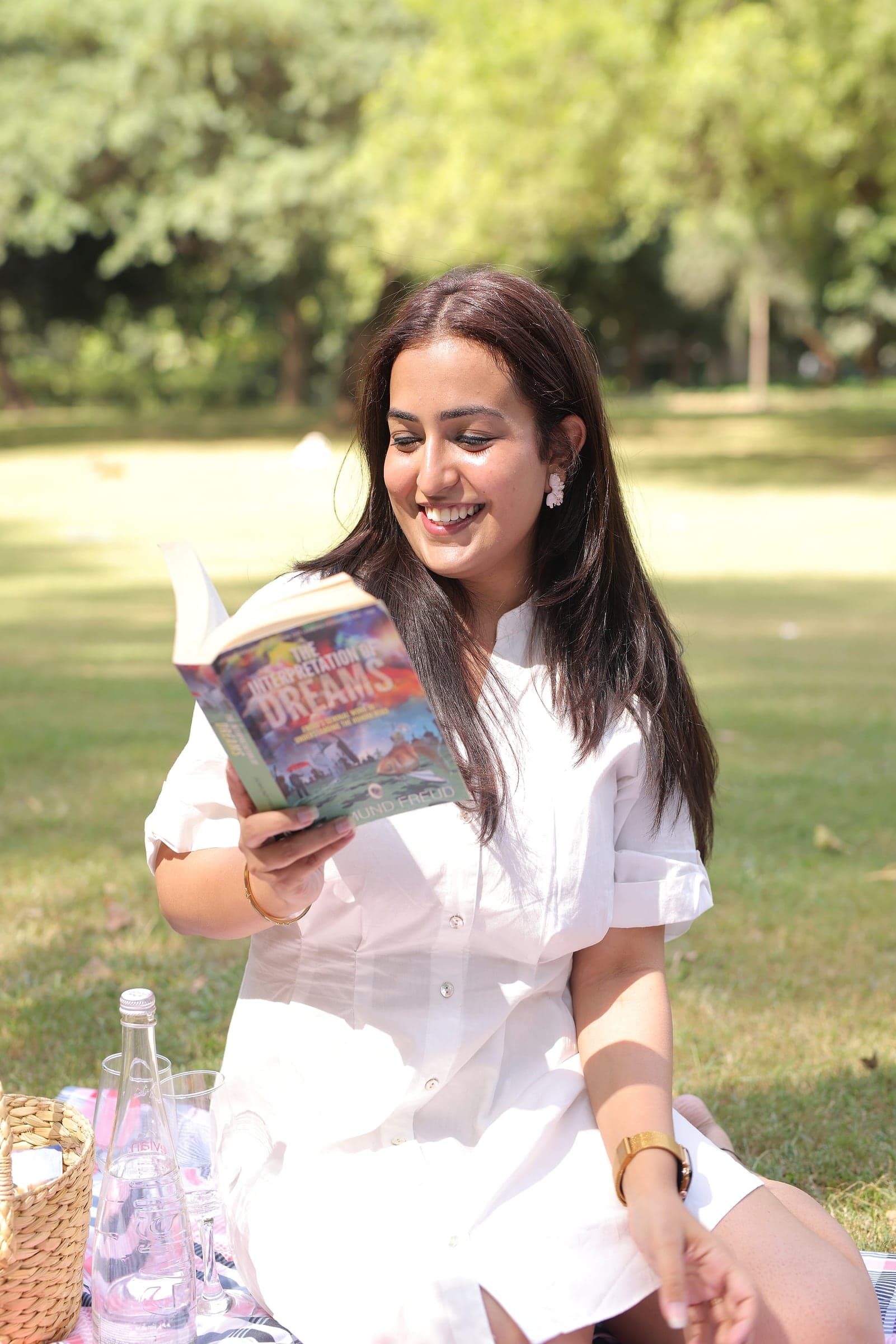 Disha laughing over a book on a picnic blanket