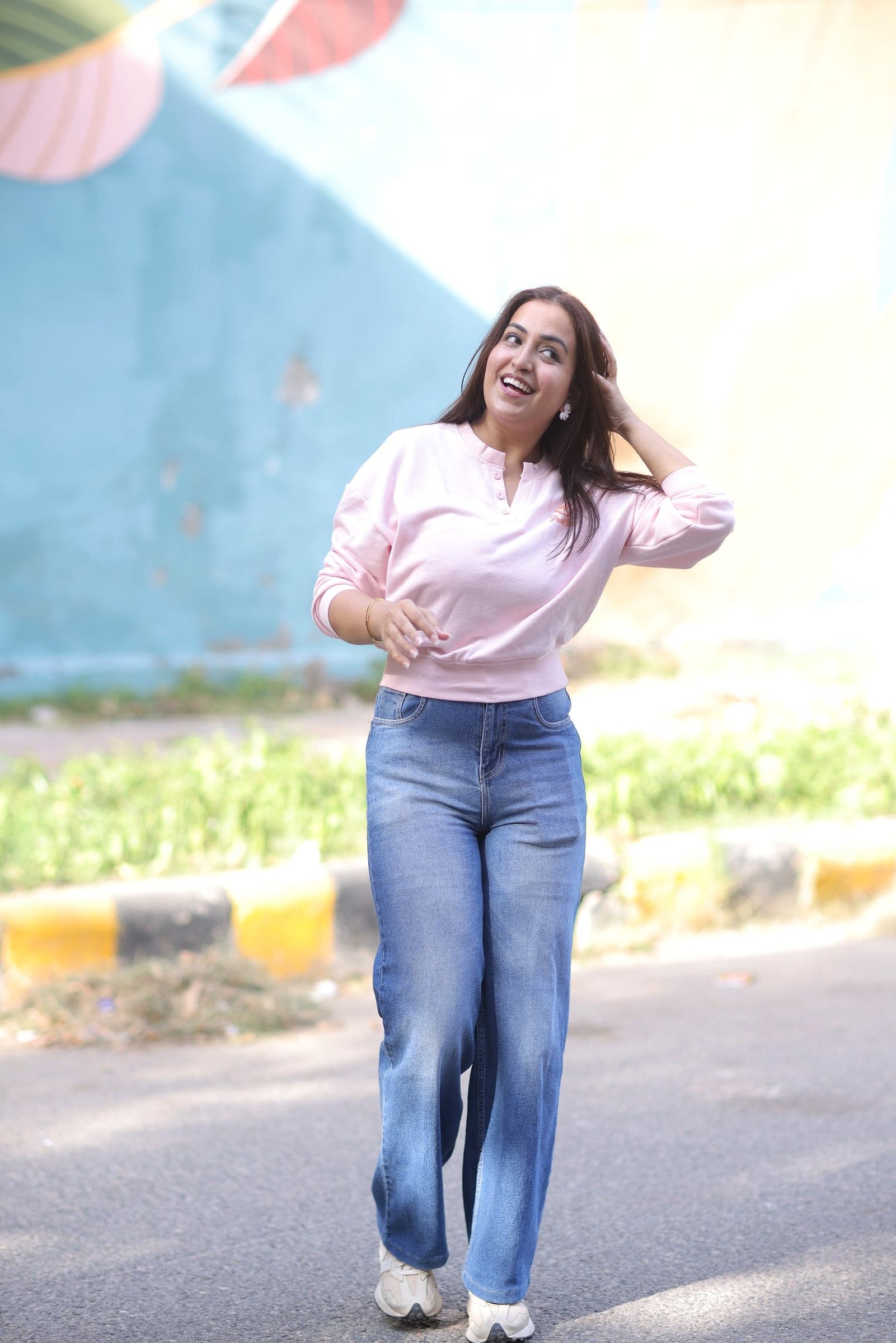 Disha walking past a painted wall