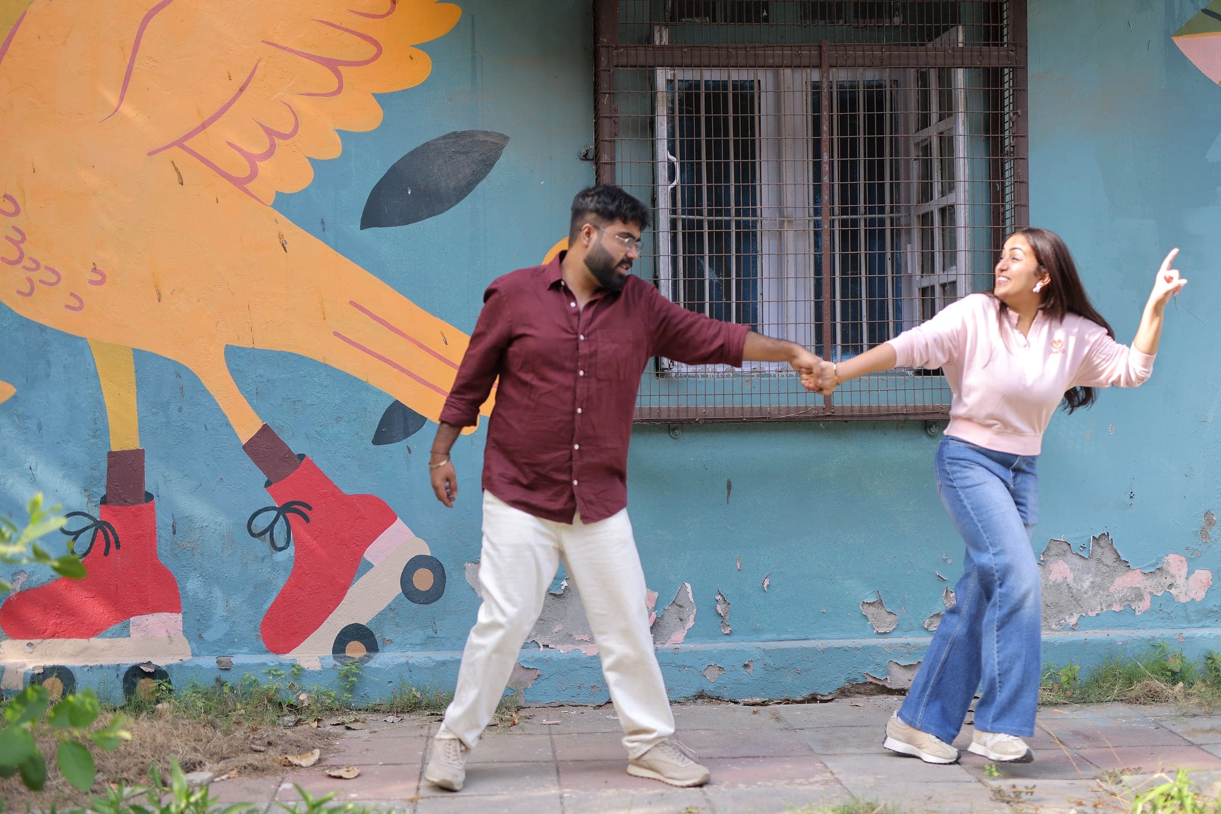 Mayank twirling Disha in front of a mural